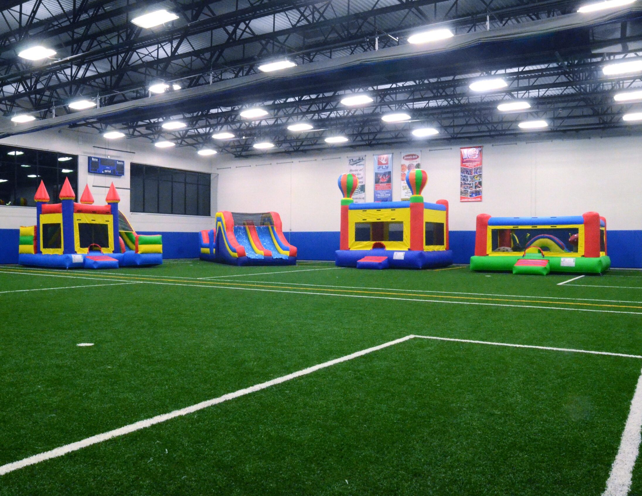 4 large inflatable bouncy houses on turf field for indoor play for daycare children and birthday parties at Westmont Yard in Westmont IL