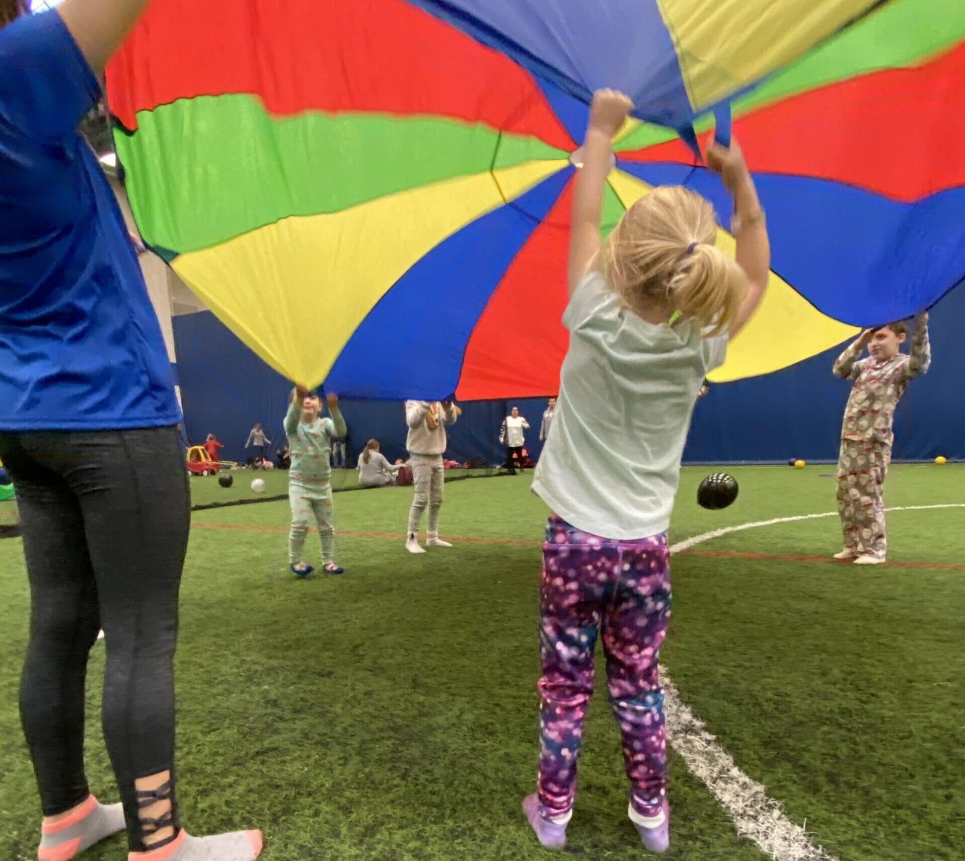 Birthday party kids playing on indoor turf fields parachute game with designated party coordinator at westmont yard indoor sports complex